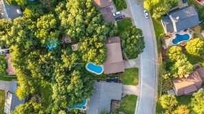 An aerial view of a residential area with multiple houses, a swimming pool, and a road. - Dog-friendly chic home w/private outdoor pool, gas grill, & enclosed backyard (San Antonio)