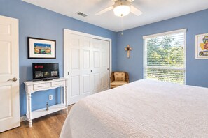 A bedroom with a bed, a desk with a television, a chair, a window with blinds, and a door. - Dog-friendly chic home w/private outdoor pool, gas grill, & enclosed backyard (San Antonio)