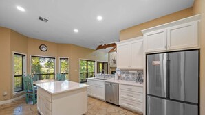 A spacious kitchen with white cabinetry, a stainless steel refrigerator, and a dining area with chairs. - Winter Texan riverfront home on Lake Seguin with dock, kayaks, beautiful views & air hockey (Seguin)