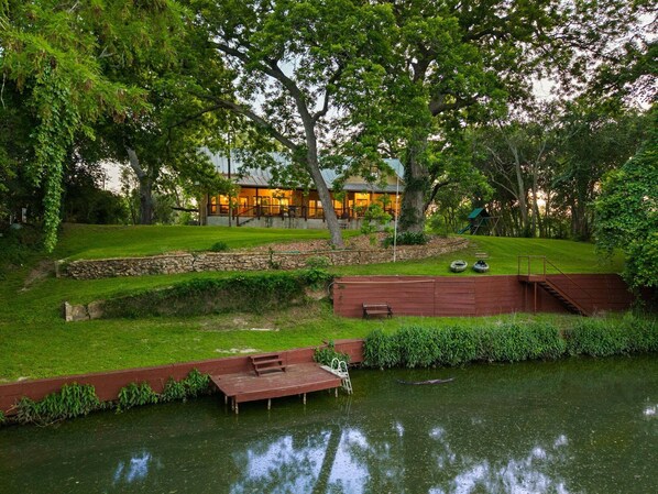 A house with a stone wall, a wooden deck, and a pond.