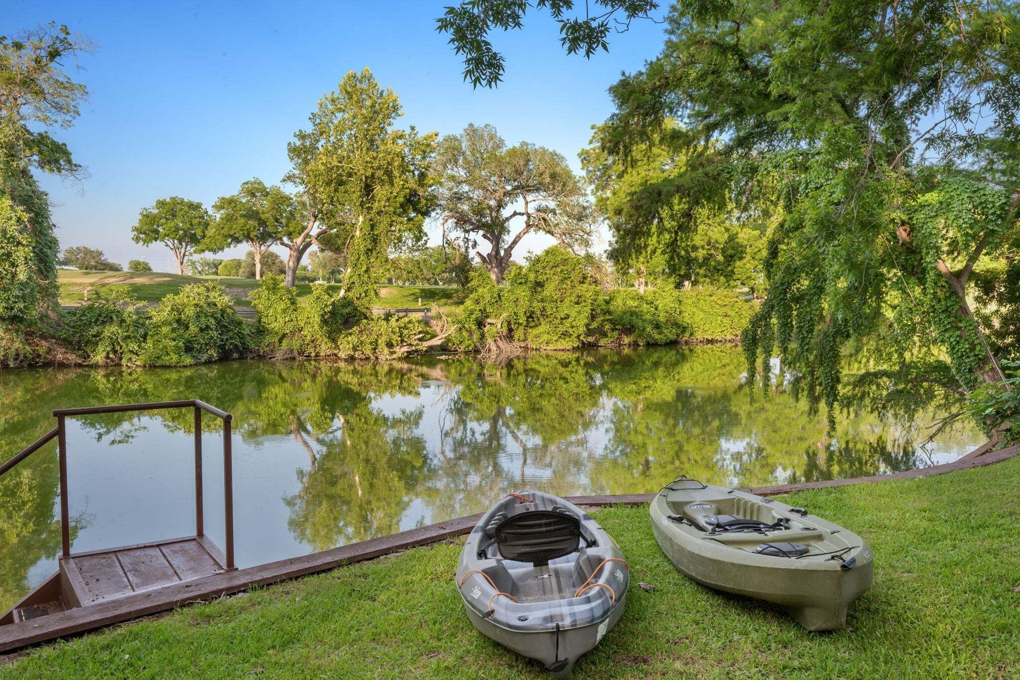 Un lago tranquilo con barcos, un muelle de madera y exuberante vegetación.