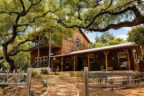 A rustic wooden building with a covered patio area, stone pathway, and outdoor seating. - Modern Hill Country Multi-unit w/kitchen, WIFI, patio, private pool & hot tubs (Wimberley)