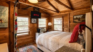 Accogliente camera in una baita di legno, con un letto, una lampada, un termosifone e un cartello che indica il servizio Netflix.