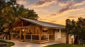 A lodge with a stone exterior, a covered patio, and a stone chimney.