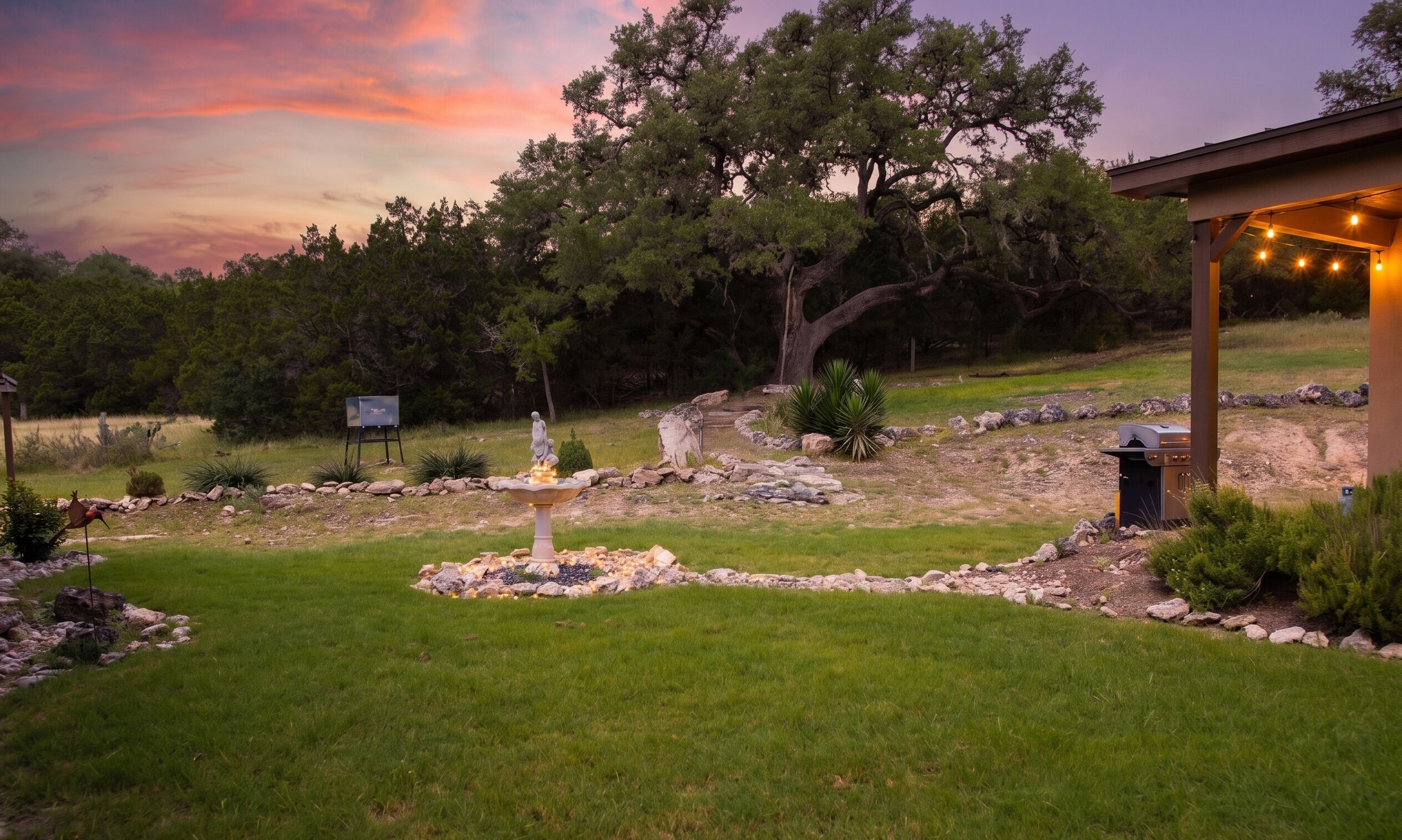 Un jardin aménagé avec une statue, une fontaine et un espace barbecue.