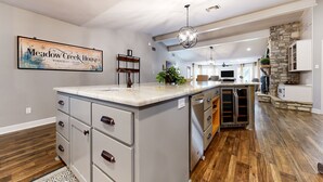 A spacious kitchen with a large island, wooden flooring, and a stone accent wall. - Serene property with two living spaces and large outdoor space - dog-friendly (Wimberley)