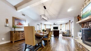 A spacious dining area with a wooden table and chairs, a chandelier, and a stone fireplace. - Serene property with two living spaces and large outdoor space - dog-friendly (Wimberley)
