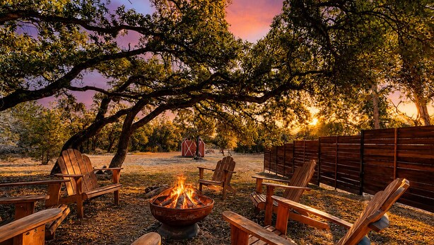 A fire pit surrounded by wooden chairs in an outdoor setting. - Serene property with two living spaces and large outdoor space - dog-friendly (Wimberley)