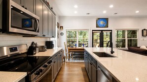 Uma cozinha moderna com eletrodomésticos de aço inoxidável, uma ilha grande e vista para o exterior.
