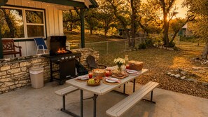 An outdoor patio with a stone wall, a grill, and a table set for a meal. - Two-Story Family-Friendly Home w/ Free WiFi, a Washer/Dryer, & an Enclosed Yard (Canyon Lake)