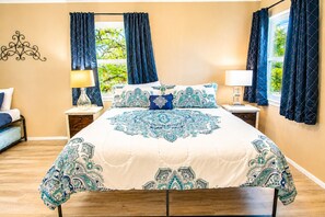 A bedroom with a large bed, two bedside tables, a nightstand, and a window with curtains. - Two-Story Family-Friendly Home w/ Free WiFi, a Washer/Dryer, & an Enclosed Yard (Canyon Lake)