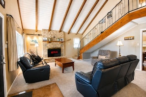 A spacious living room with a stone fireplace, leather sofas, a wooden coffee table, and a staircase. - Two-Story Family-Friendly Home w/ Free WiFi, a Washer/Dryer, & an Enclosed Yard (Canyon Lake)