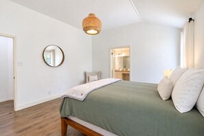 A bedroom with a bed, a bedside table, a mirror, and a hanging light fixture. - Beautiful dog-friendly home with fireplace, large yard, hammock, W/D, and AC (Buda)