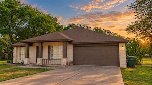 Une maison de plain-pied avec une porte de garage marron, un porche à colonnes et une pelouse bien entretenue.