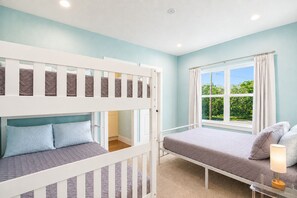 Une chambre avec des lits superposés, une fenêtre avec des rideaux et une table de chevet avec une lampe.
