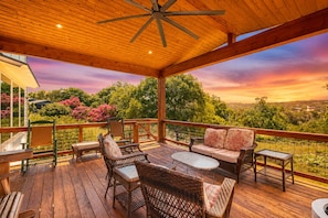 A covered outdoor deck with wicker furniture, a ceiling fan, and a scenic view of trees and hills. - Lakeside Serenity with Private Waterfront Access on Canyon Lake (Canyon Lake)