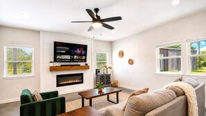 Un salon avec une cheminée, un téléviseur fixé au mur, un ventilateur de plafond et un canapé.