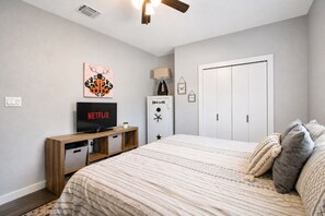 Ein Schlafzimmer mit einem Bett, einem Fernseher auf einem Holzschrank, einem Kleiderschrank und einer Tür.