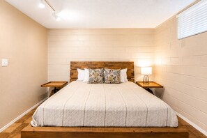 Una camera da letto con una testiera in legno, un letto con copriletto trapuntato, due comodini con lampade e una finestra con persiane.