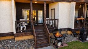 A covered outdoor area with a barbecue grill, wooden steps, and a seating area with chairs. - Two-Story Golf Course Front Condo w/Balconies, Free WiFi, Gas Grill, Central A/C (Canyon Lake)