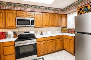 A kitchen with wooden cabinets, a stainless steel refrigerator, a microwave, an oven, and a coffee maker. - Two-Story Golf Course Front Condo w/Balconies, Free WiFi, Gas Grill, Central A/C (Canyon Lake)