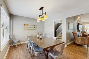 Een eethoek met een houten tafel, metalen stoelen en een hanglamp.