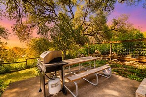 Een buitenbarbecue met een grill, een tafel en een gasfles.