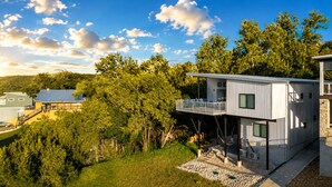 A modern two-story house with a balcony, surrounded by lush greenery and trees. - Modern lakefront home with multi levels and gorgeous views and Winter Texan Friendly (Canyon Lake)