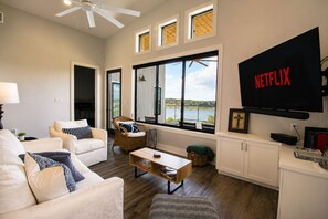Ein Wohnzimmer mit Sofa, Sessel, Couchtisch und einem an der Wand befestigten Fernseher.