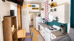 Een kleine keuken met een fornuis, spoelbak en een eethoek met een tafel en stoelen.