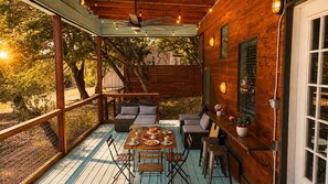 Een terras buiten met een houten terras, zithoek en een eettafel.
