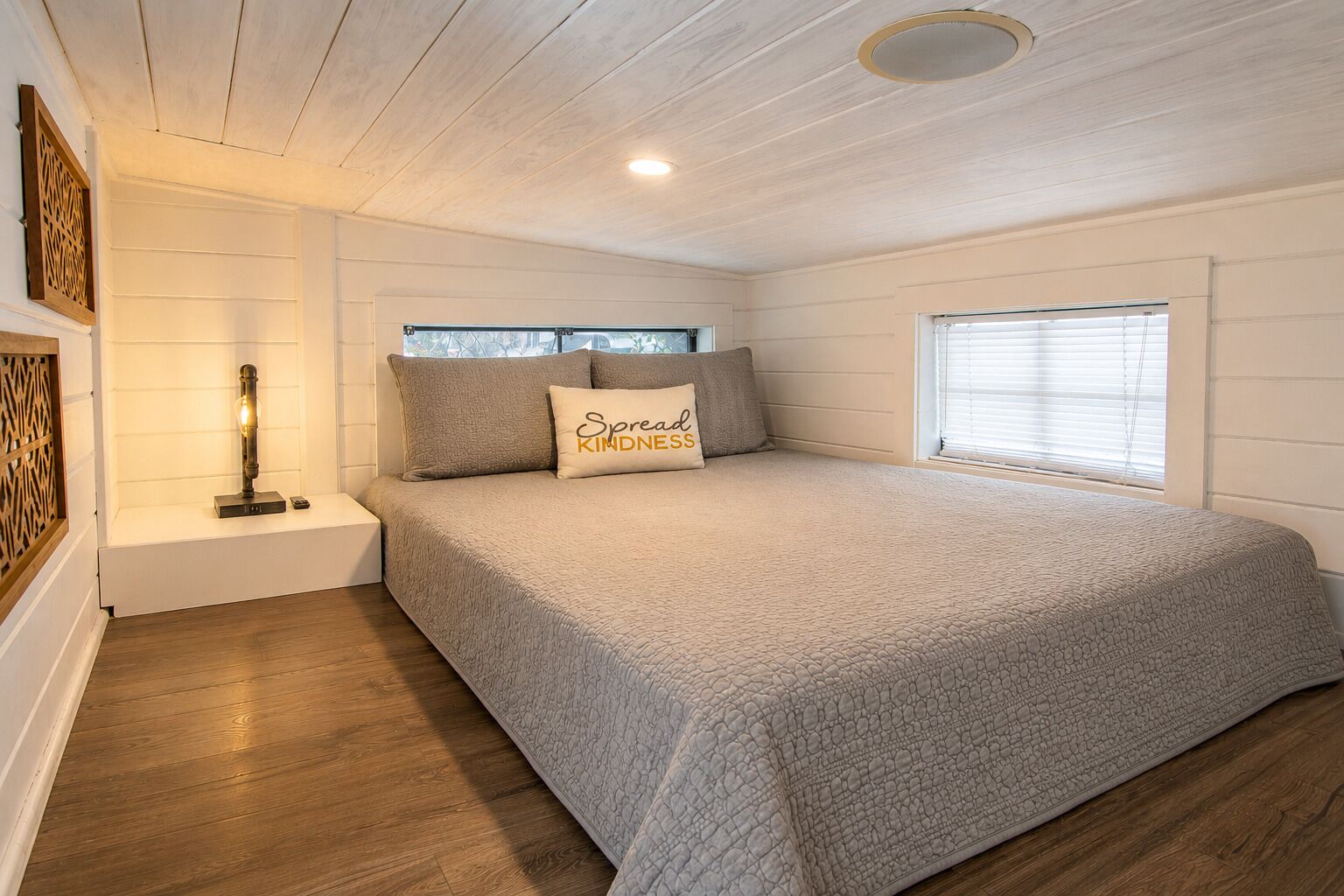 Une chambre à coucher avec un lit, une table de chevet, une lampe et une fenêtre.