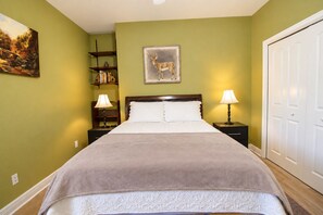 A neatly made bed with a headboard, two bedside lamps, a bookshelf, and a painting on the wall. - Stargazers' dream home on 1.5 acres w/ telescope-near wineries-Dogs ok (Dripping Springs)