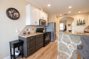 A modern kitchen with white cabinets, a black countertop, and a stone backsplash. - Stargazers' dream home on 1.5 acres w/ telescope-near wineries-Dogs ok (Dripping Springs)