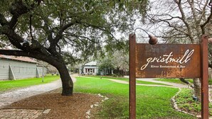 A rustic sign for Gristmill River Restaurant & Bar, surrounded by a landscaped garden with a brick pathway. - Gruene Envy – a first floor Poolside Condo with Guadalupe River Access (New Braunfels)