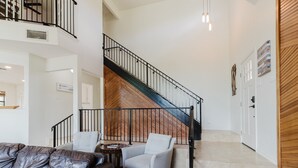 A spacious interior with a staircase, a leather sofa, and a dining area. - Idyllic waterfront getaway with private hot tub & deck views - near golf (New Braunfels)