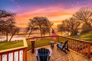 Una terraza con sillas Adirondack, baranda de madera y una bandera estadounidense.