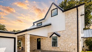 A two-story house with a stone facade, a garage, and a covered entryway. - Idyllic waterfront getaway with private hot tub & deck views - near golf (New Braunfels)