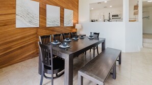 A dining area with a wooden wall, a long table, and chairs. - Idyllic waterfront getaway with private hot tub & deck views - near golf (New Braunfels)