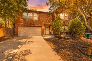 A two-story brick house with a garage, a front door, and a small porch area. - Dog-friendly home with huge yard, covered patio, & fireplace (San Antonio)