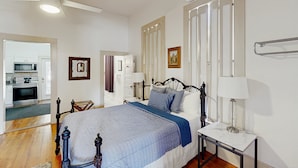 Une chambre à coucher comprenant un lit, des tables de chevet, un ventilateur de plafond et un appareil de climatisation.