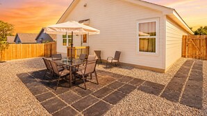 Ein Bungalow mit Terrasse, Tisch und Stühlen sowie einem Holzzaun.