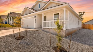 Ein zweistöckiges Haus mit überdachter Veranda, Garage und gepflegtem Schotterweg.