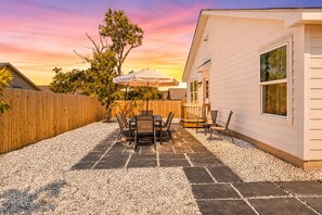 A patio with a table and chairs, a wooden fence, and a house with a window. - Lackland BMT Graduation stay with streaming & backyard (San Antonio)