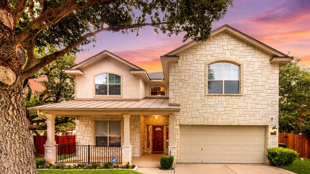 A two-story house with a stone facade, a covered porch, and a garage. - 2-story house with back patio, grill, streaming, washer/dryer, & 2 living areas (San Antonio)
