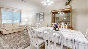 A dining area with a table set for four, surrounded by white chairs. - 2-story house with back patio, grill, streaming, washer/dryer, & 2 living areas (San Antonio)