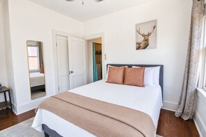 A bedroom with a bed, a mirror, a door, and a wall-mounted artwork. - One bedroom cozy retreat by the Pearl and the vibrant St. Mary (San Antonio)