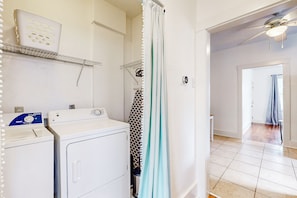 A laundry area with a washing machine, dryer, and a shelf with a laundry basket. - One bedroom cozy retreat by the Pearl and the vibrant St. Mary (San Antonio)