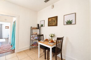 A dining area with a wooden table, chairs, a bookshelf, and framed artwork on the wall. - One bedroom cozy retreat by the Pearl and the vibrant St. Mary (San Antonio)