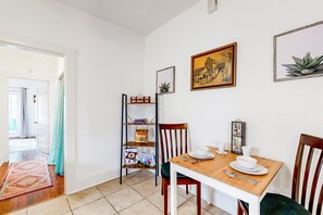 Ein Essbereich mit Holztisch, Stühlen und einem Regal mit Büchern und einer Pflanze.